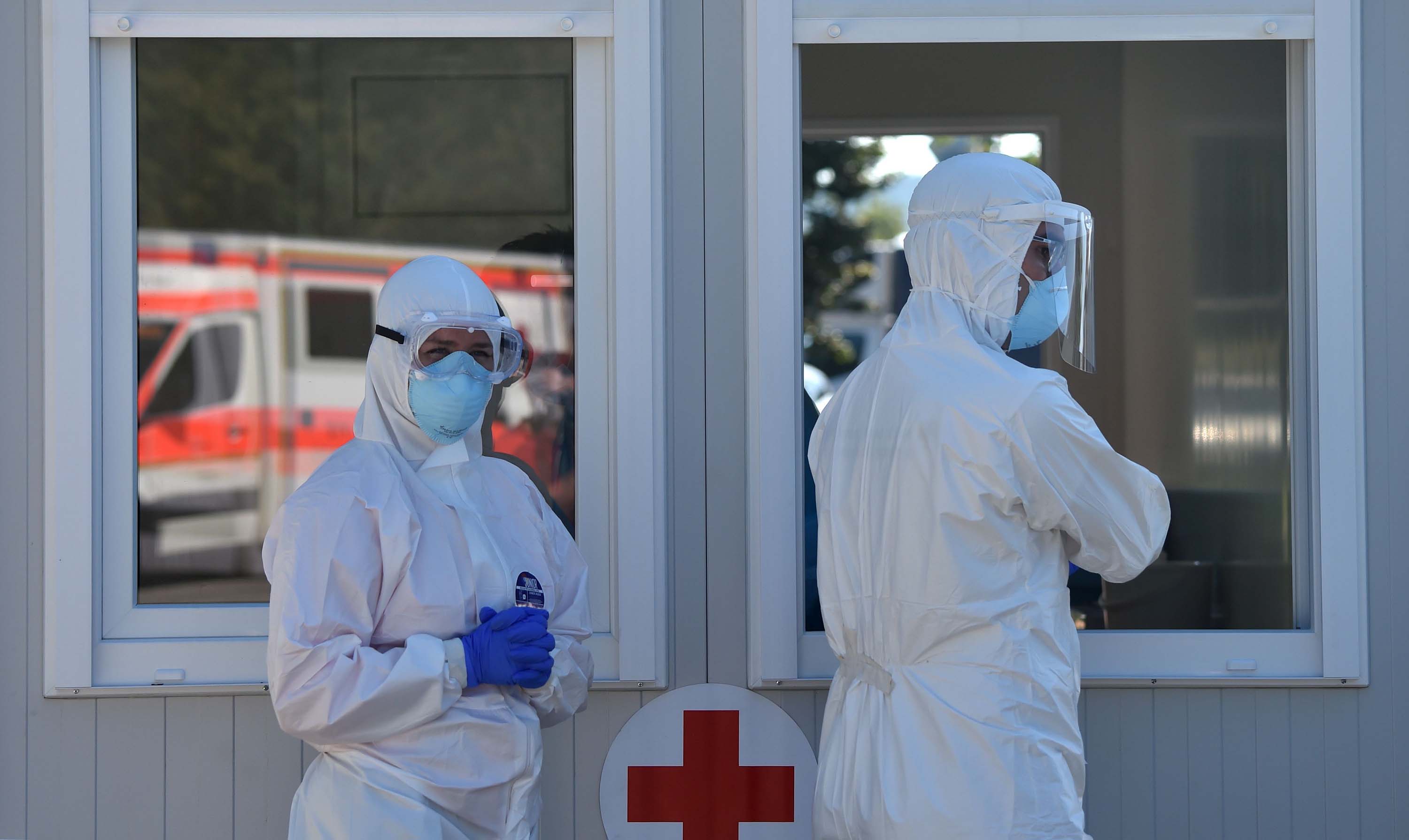 Health workers wear protective clotes while taking samples of persons arriving in their cars at a new coronavirus COVID-19 testing station for travelers from the motorway at the motorway service area Hochfelln near Ruhpolding, southern Germany, on July 30, 2020. (Photo by Christof STACHE / AFP) (Photo by CHRISTOF STACHE/AFP via Getty Images)